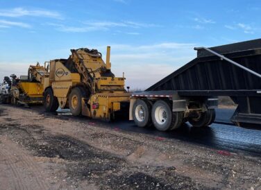paving trucks at SH 302 for widening and improvements