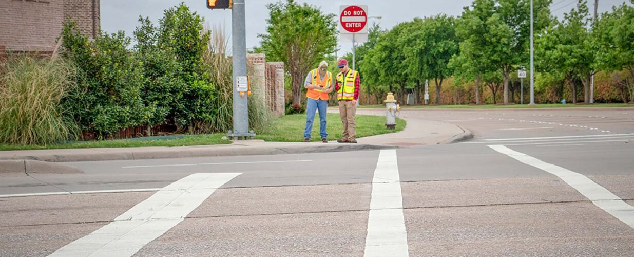 two workers standing across street crosswalk