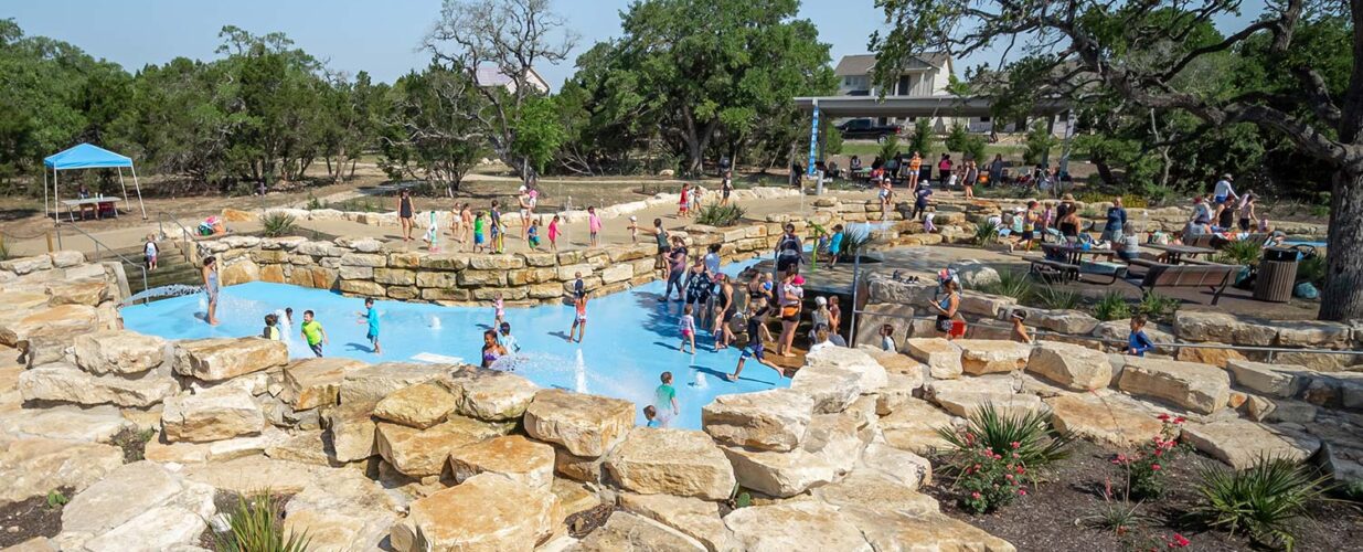 splash area with families and kids playing at Leander Lake Park