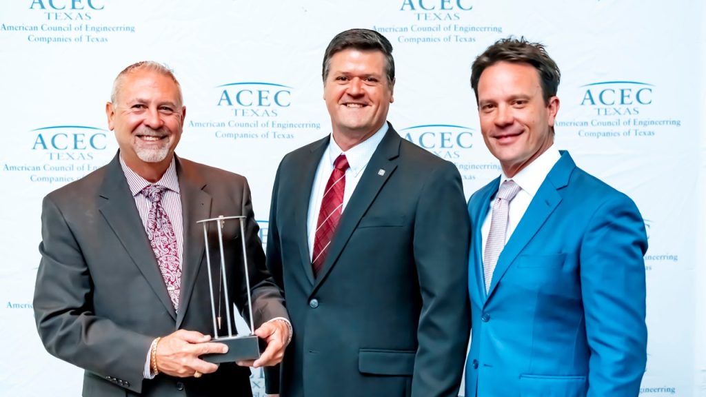 group of 3 attendees and Halff employee Edward Herolt accepting 2023 ACEC Texas Engineering Excellence Award at gala
