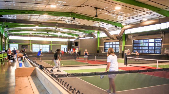 People of all ages playing indoor pickleball at Chicken N Pickle in Grand Prairie, Texas