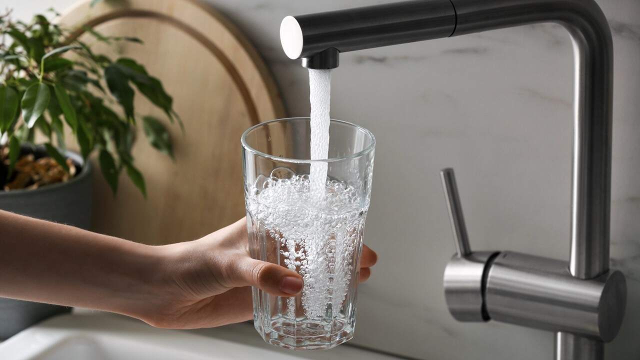 glass of water being filled at a kitchen sink faucet