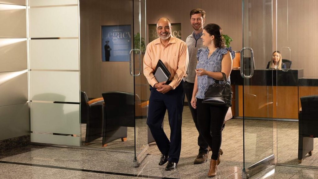 Halff engineers and employees talking, smiling and walking out the glass lobby door at front reception area