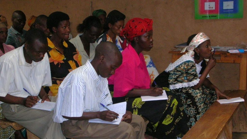 Children and teens in a classroom doing school in Kiziba